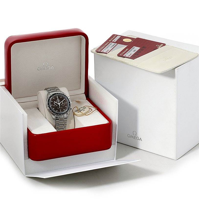 The image shows an Omega Speedmaster 311.30.42.30.13.001 Men's Stainless Steel Brown Dial 311.30.42.30.13.001 Men's Stainless Steel Brown Dial watch in its red case, accompanied by an instruction booklet, warranty card, and tags.