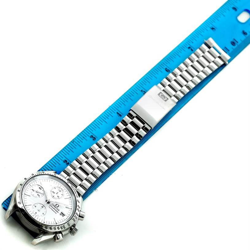 The Omega Speedmaster Men's Stainless Steel White Dial Men's Stainless Steel White Dial watch is shown at a diagonal angle with its bracelet extended next to a blue ruler for scale.