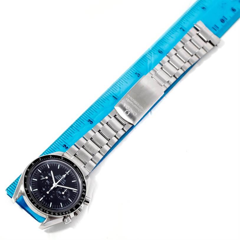 The Omega Speedmaster 3570.50.00 Men
s Stainless Steel Black Dial 3570.50.00 Men
s Stainless Steel Black Dial watch is viewed from a top-down angle, showing the face, bezel, pushers, bracelet, and clasp alongside a ruler.