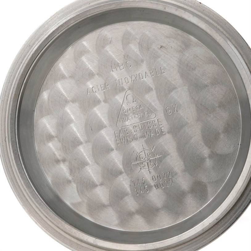 The image displays the interior of an Omega Speedmaster 3570.50.00 Men
s Stainless Steel Black Dial 3570.50.00 Men
s Stainless Steel Black Dial case back, showing inscriptions and textured patterns.