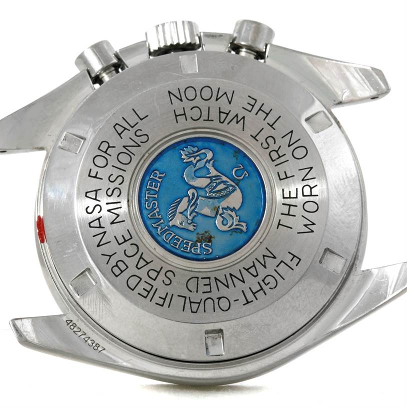 The image shows the backside of an Omega Speedmaster Men's Stainless Steel Black Dial Men's Stainless Steel Black Dial watch, displaying the engraved text and emblem.