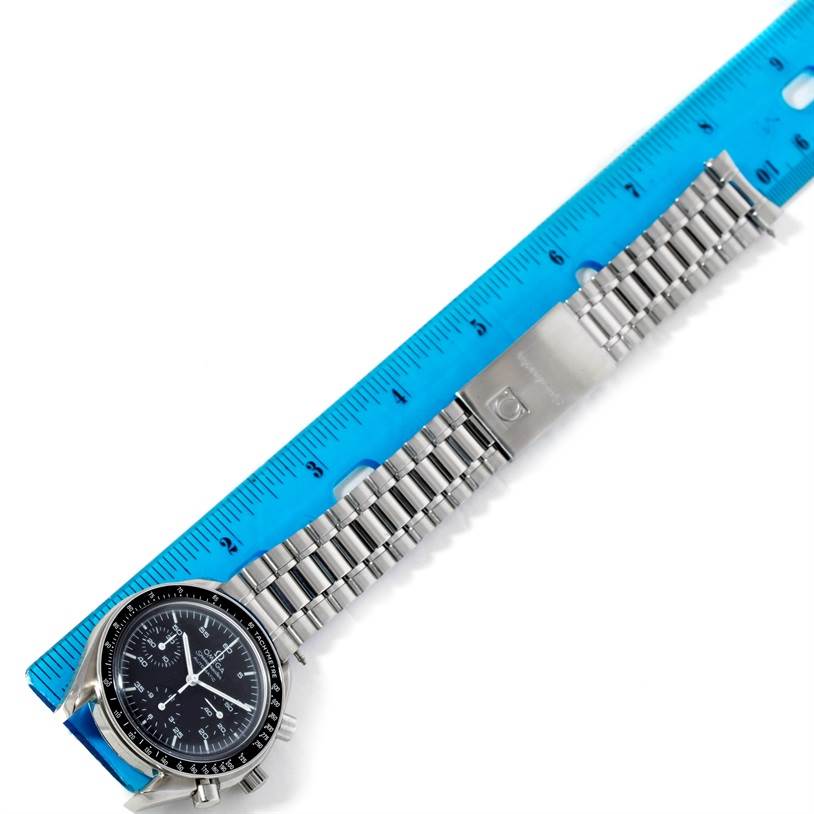 The image shows an Omega Speedmaster 3510.50.00 Men's Stainless Steel Black Dial 3510.50.00 Men's Stainless Steel Black Dial watch, photographed from above, with its face and metal bracelet laid alongside a blue ruler.