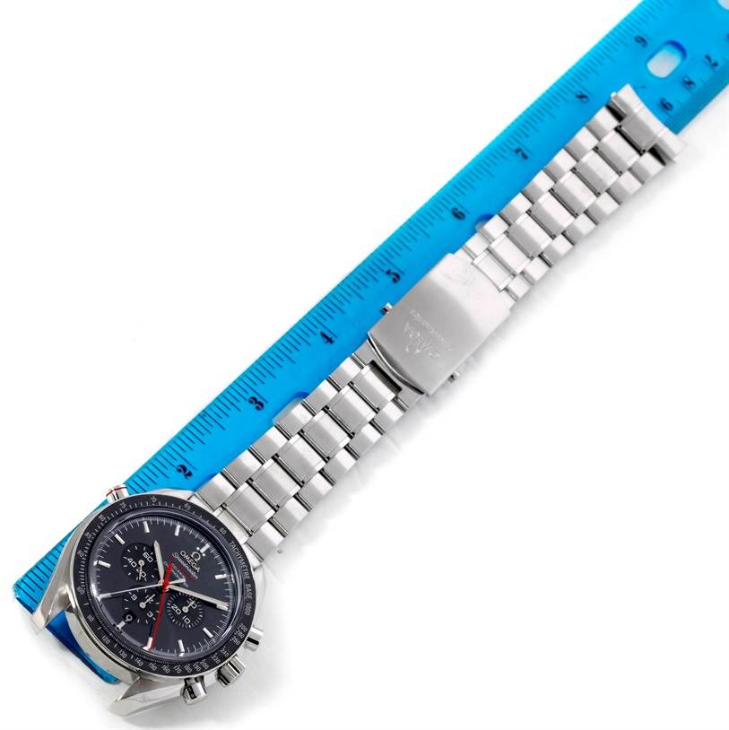 This image shows an Omega Speedmaster 311.30.44.51.01.001 Men's Stainless Steel Black Dial 311.30.44.51.01.001 Men's Stainless Steel Black Dial watch laid flat alongside a blue ruler, displaying its metal bracelet and clasp.