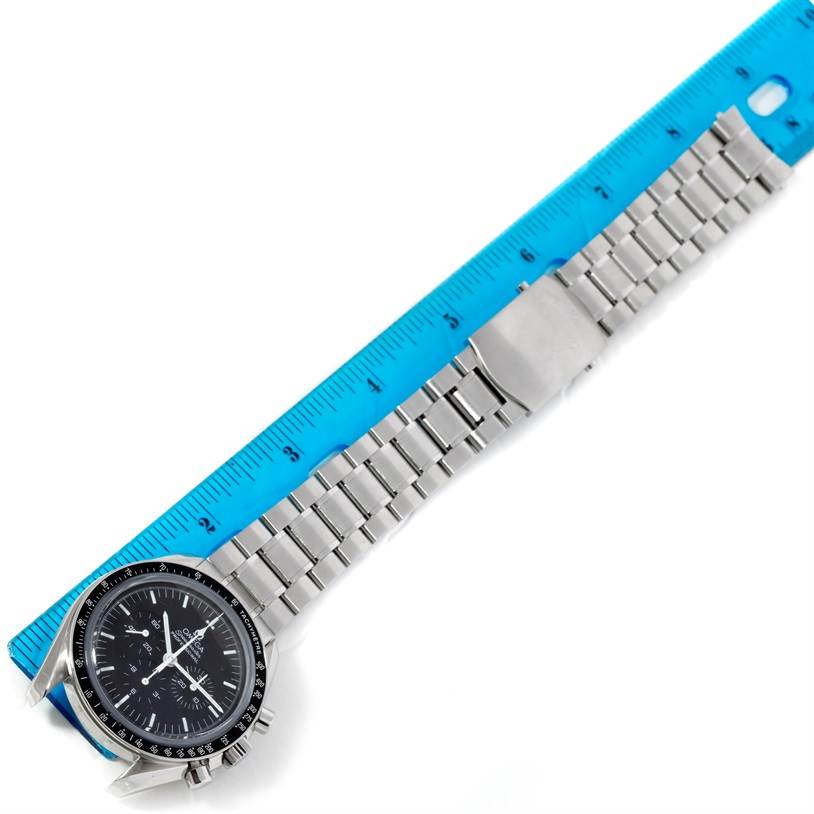 The image shows an Omega Speedmaster 3573.50.00 Men
s Stainless Steel Black Dial 3573.50.00 Men
s Stainless Steel Black Dial watch with its band measured against a blue ruler, taken from an overhead angle.