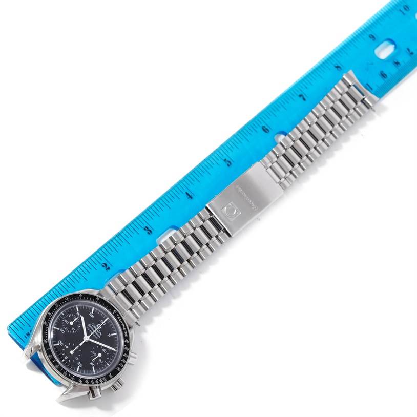 The Omega Speedmaster 3510.50.00 Men
s Stainless Steel Black Dial 3510.50.00 Men
s Stainless Steel Black Dial watch is displayed at a diagonal angle, showing the face, stainless steel bracelet, and clasp next to a blue ruler.