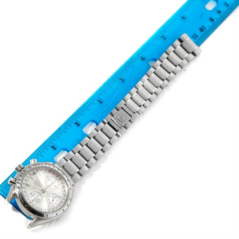 The Omega Speedmaster 3523.30.00 Men's Stainless Steel Silver Dial 3523.30.00 Men's Stainless Steel Silver Dial watch is shown from an overhead view, featuring its face, bezel, and metal bracelet next to a blue ruler.