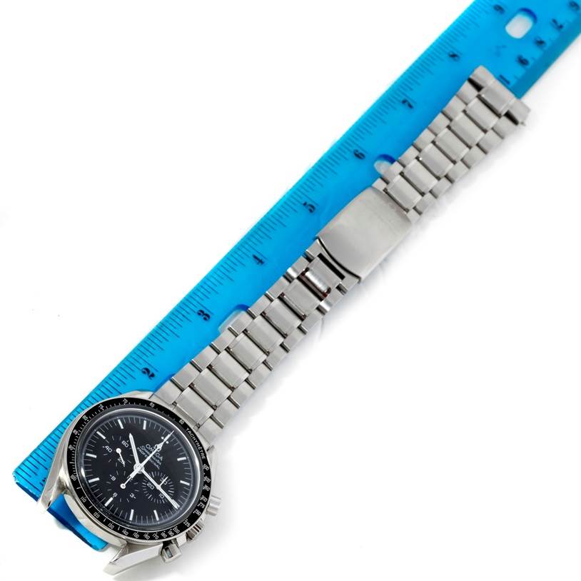 The Omega Speedmaster 3560.50.00 Men's Stainless Steel Black Dial 3560.50.00 Men's Stainless Steel Black Dial watch is shown from a top-down angle, displaying its face, bezel, and metal bracelet lying next to a ruler.