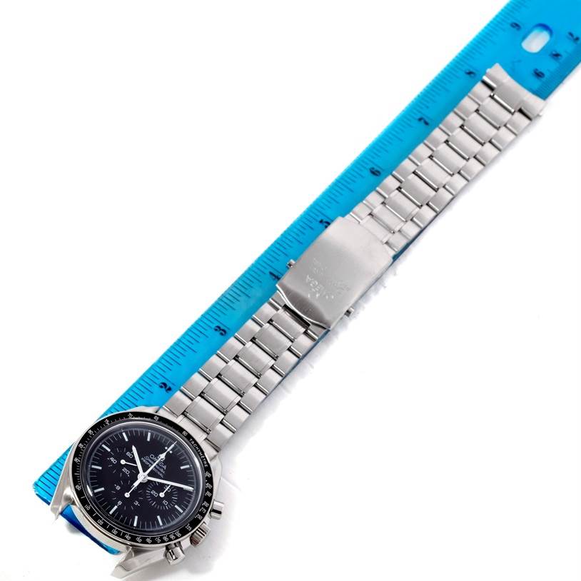 The Omega Speedmaster 3570.50.00 Men
s Stainless Steel Black Dial 3570.50.00 Men
s Stainless Steel Black Dial watch is shown from an overhead angle, featuring its face, metal bracelet, and clasp, alongside a ruler.