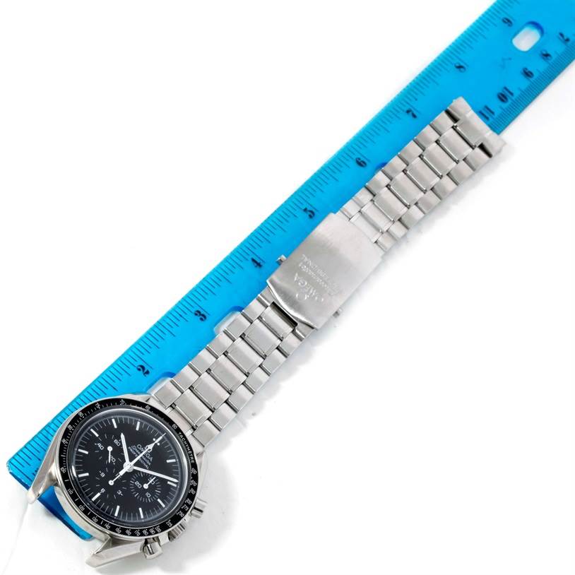 The image shows the Omega Speedmaster 3570.50.00 Men
s Stainless Steel Black Dial 3570.50.00 Men
s Stainless Steel Black Dial watch laid flat, displaying the face, crown, and entire metal bracelet next to a ruler.