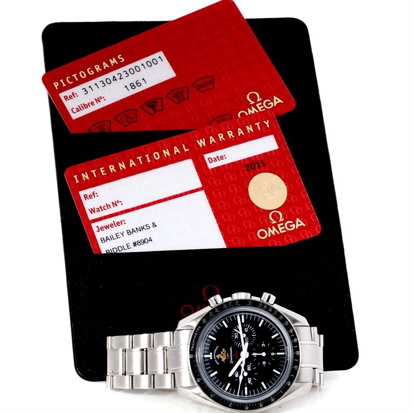 The image shows an Omega Speedmaster 311.30.42.30.01.001 Men
s Stainless Steel Black Dial 311.30.42.30.01.001 Men
s Stainless Steel Black Dial watch flat-lay with its international warranty and pictogram cards.