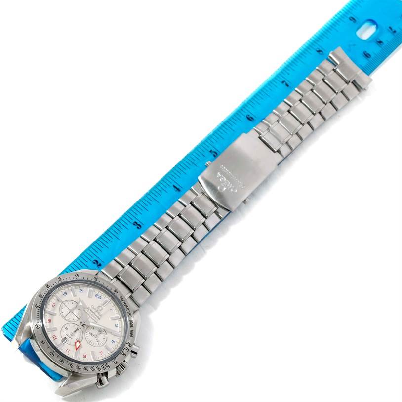 This image shows an Omega Speedmaster 3581.30.00 Men
s Stainless Steel White Dial 3581.30.00 Men
s Stainless Steel White Dial watch displayed with its face and metal bracelet extended next to a blue ruler.