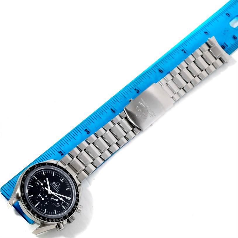 The image shows an Omega Speedmaster 3573.50.00 Men
s Stainless Steel Black Dial 3573.50.00 Men
s Stainless Steel Black Dial watch laid flat next to a ruler, displaying the face, bracelet, and clasp.