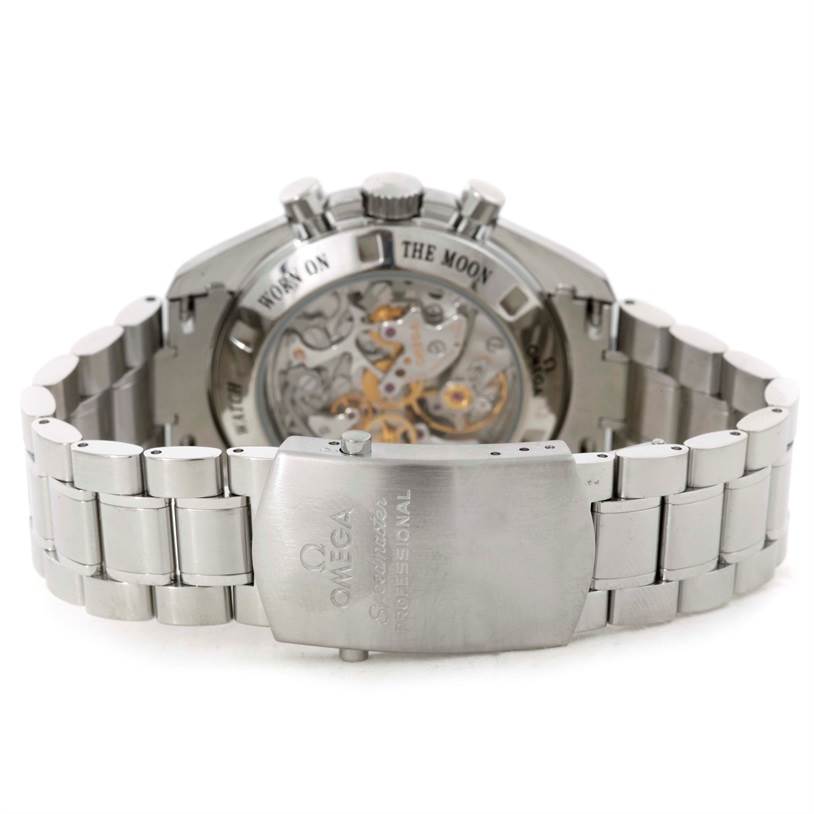 The image shows the back view of an Omega Speedmaster 3573.50.00 Men
s Stainless Steel Black Dial 3573.50.00 Men
s Stainless Steel Black Dial watch, highlighting its bracelet and open case back detailing "Flight-Qualified" and "Moon."