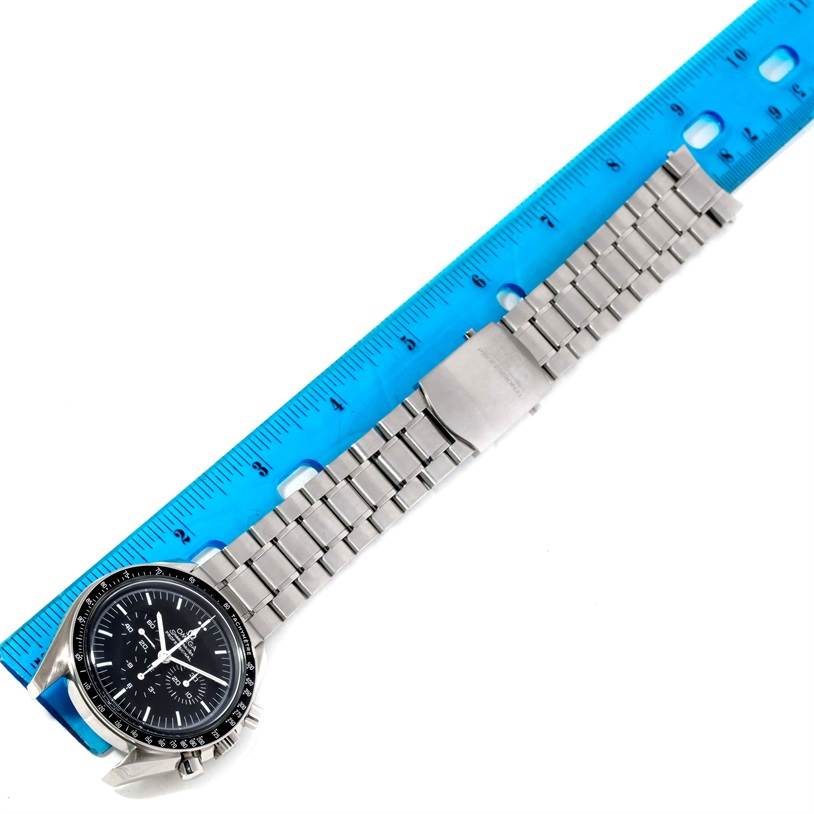 The Omega Speedmaster 3570.50.00 Men
s Stainless Steel Black Dial 3570.50.00 Men
s Stainless Steel Black Dial watch is shown flat with its stainless steel bracelet extended along a blue ruler.