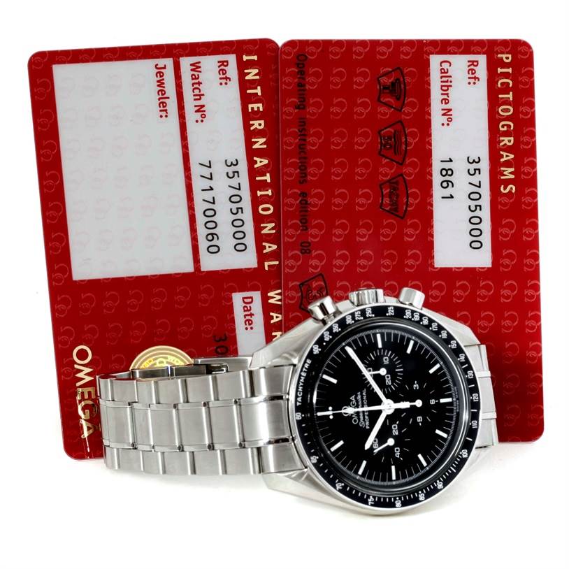 The image shows an Omega Speedmaster 3570.50.00 Men
s Stainless Steel Black Dial 3570.50.00 Men
s Stainless Steel Black Dial watch and its two red warranty and information cards.