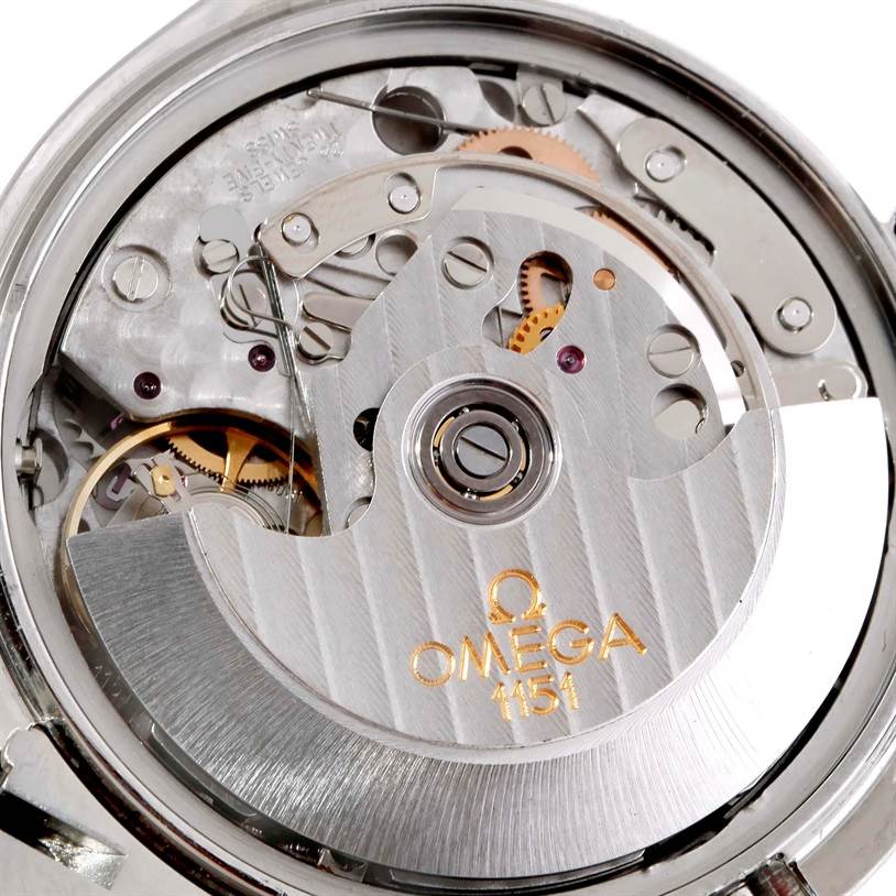 This image features a close-up of the Omega Speedmaster 3520.50.00 Men
s Stainless Steel Black Dial 3520.50.00 Men
s Stainless Steel Black Dial
s movement mechanism with visible gears and the rotor engraved with "OMEGA 1151."