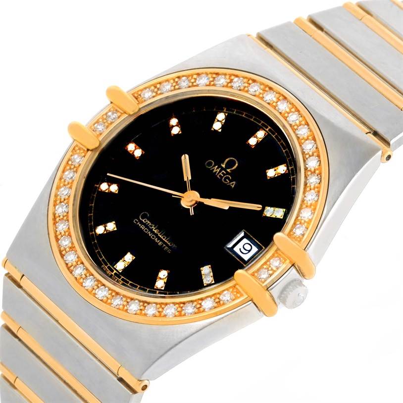 The image shows an angled view of the Omega Constellation Men's Steel and Gold (two tone) Black Dial Men's Steel and Gold (two tone) Black Dial watch, highlighting the diamond-studded bezel, black dial, and date window.