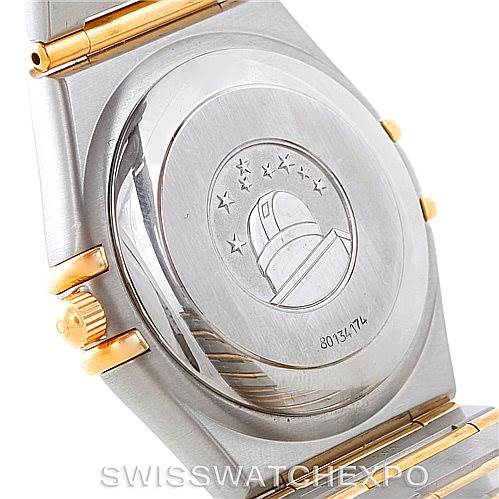 The image shows the case back of an Omega Constellation 1202.30.00 Men
s Steel and Gold (two tone) Silver Dial 1202.30.00 Men
s Steel and Gold (two tone) Silver Dial watch, with a focus on its emblem and serial number.
