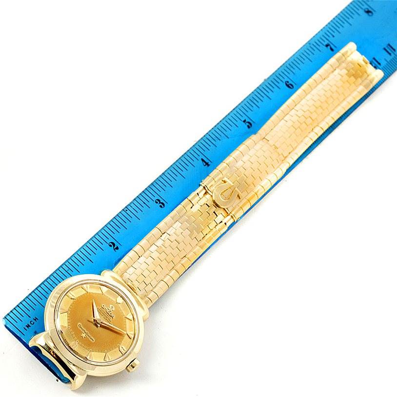 The Omega Constellation 14365 Men's Yellow Gold Champagne Dial 14365 Men's Yellow Gold Champagne Dial watch is shown at an angled flat-lay view, featuring its face, bracelet, and clasp, with a ruler for scale.