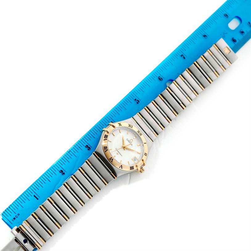 The Omega Constellation 1312.30.00 Men's Steel and Gold (two tone) Silver Dial 1312.30.00 Men's Steel and Gold (two tone) Silver Dial watch is shown from a top view with a blue ruler placed alongside its metal bracelet.