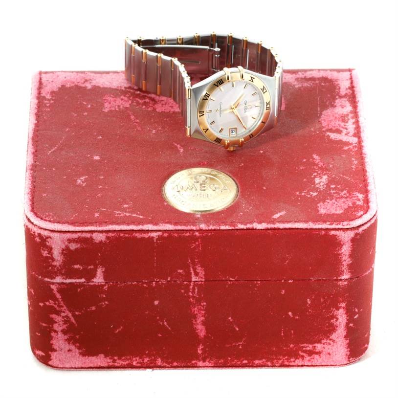 The Constellation model by Omega is displayed on a red box, showing the face, bezel, and part of the bracelet.