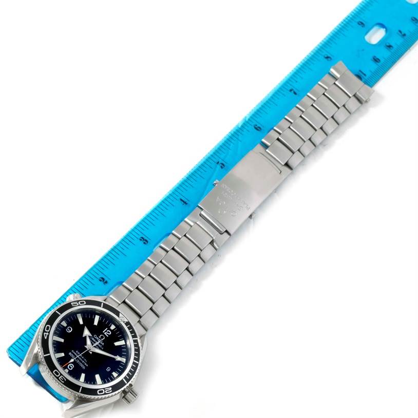 An Omega Planet Ocean 2201.50.00 Men
s Stainless Steel Black Dial 2201.50.00 Men
s Stainless Steel Black Dial watch is shown flat with its metal band next to a blue ruler for measurement.