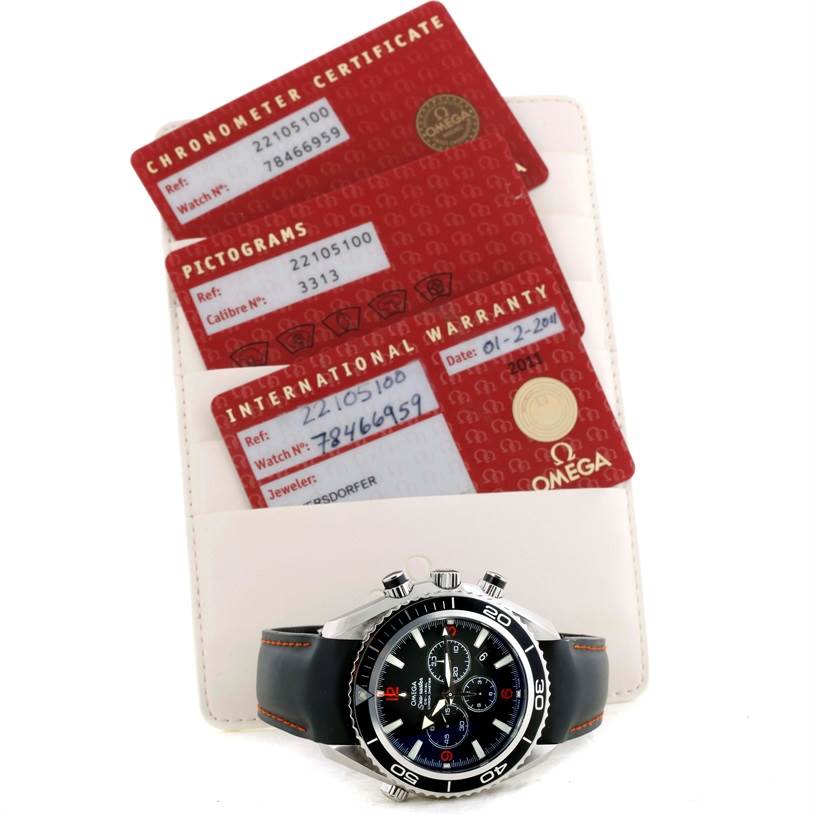 The image shows an Omega Planet Ocean 2210.51.00 Men
s Stainless Steel Black Dial 2210.51.00 Men
s Stainless Steel Black Dial watch with a front view, accompanied by its chronometer certificate, pictograms, and international warranty cards.