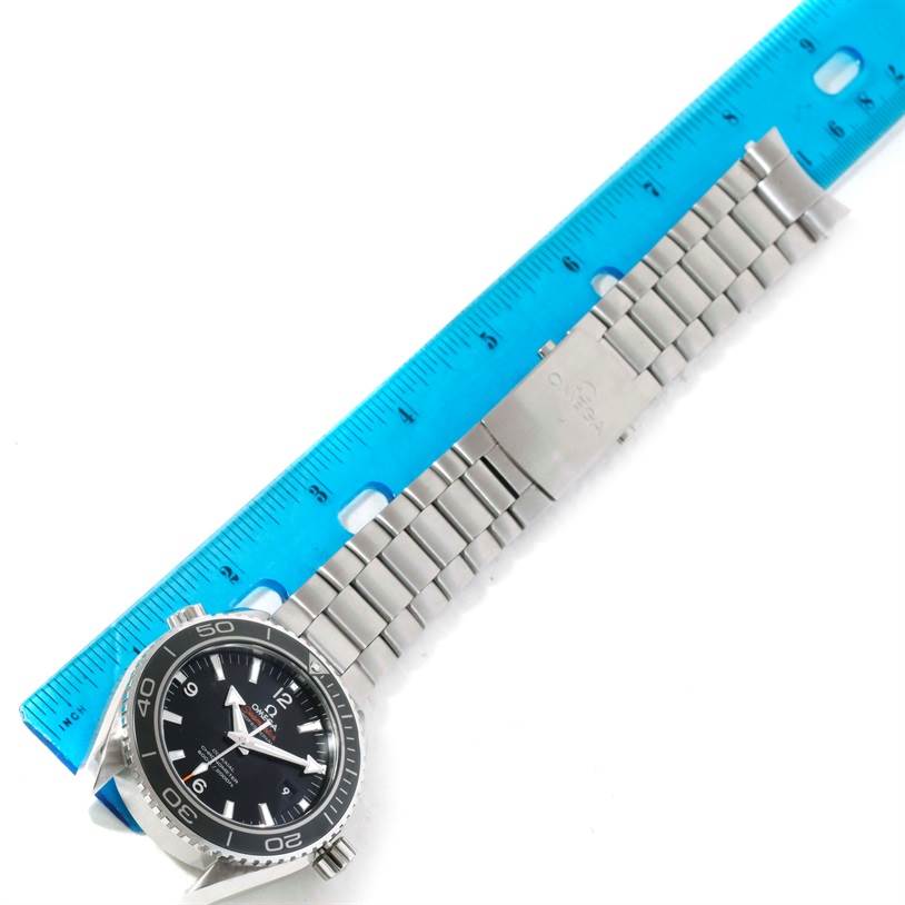 The Omega Planet Ocean 232.30.46.21.01.003 Men's Stainless Steel Black Dial 232.30.46.21.01.003 Men's Stainless Steel Black Dial watch is shown flat with its stainless steel bracelet extended alongside a blue ruler.