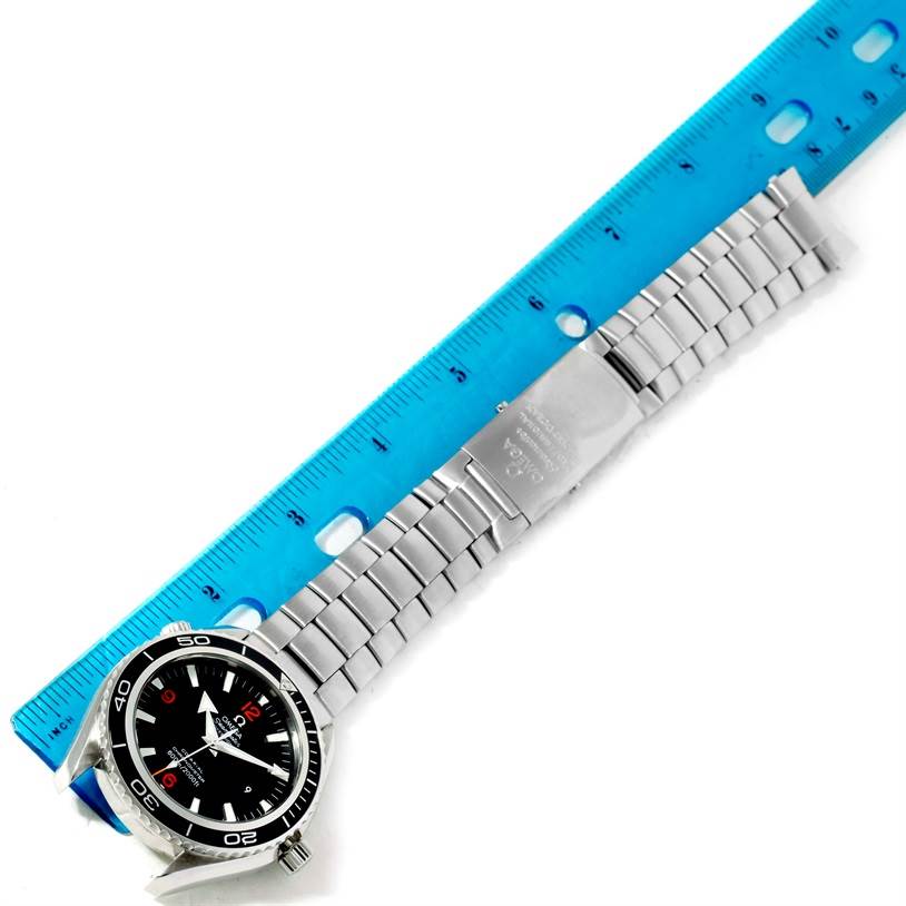 The Omega Planet Ocean 85484047 Men's Stainless Steel Black Dial 85484047 Men's Stainless Steel Black Dial watch is shown from a top-down angle beside a ruler, displaying its face and metal bracelet.