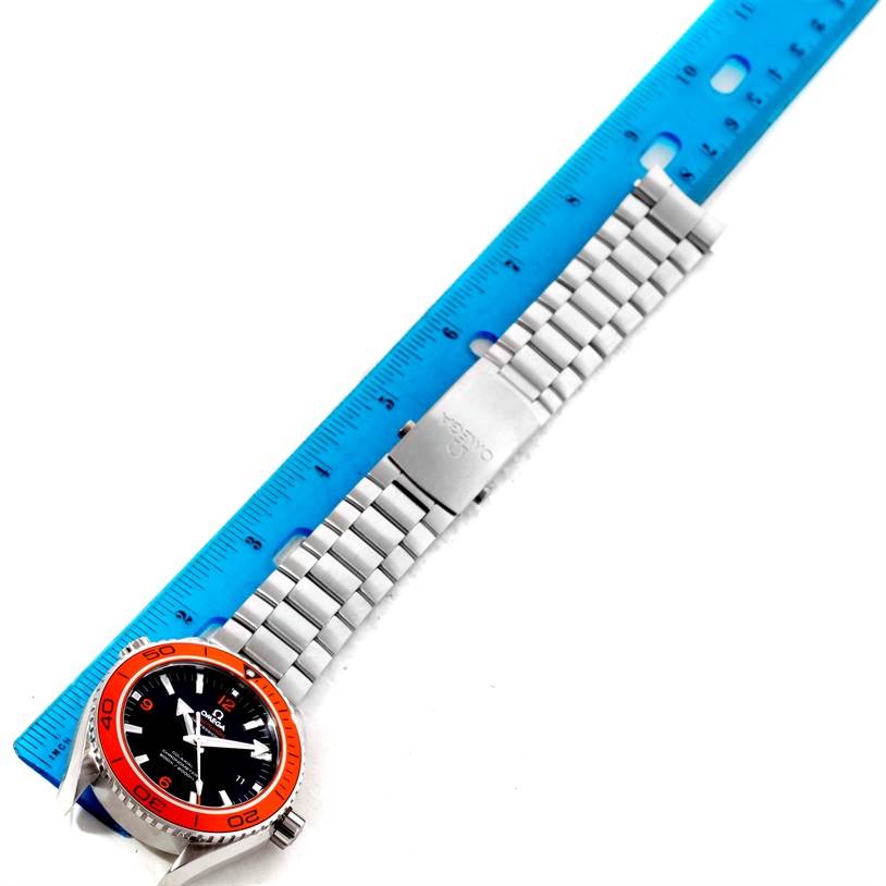 The Omega Planet Ocean 232.30.46.21.01.002 Men
s Stainless Steel Black Dial 232.30.46.21.01.002 Men
s Stainless Steel Black Dial watch is shown from a top-down angle, highlighting its face, bezel, and bracelet against a blue ruler.