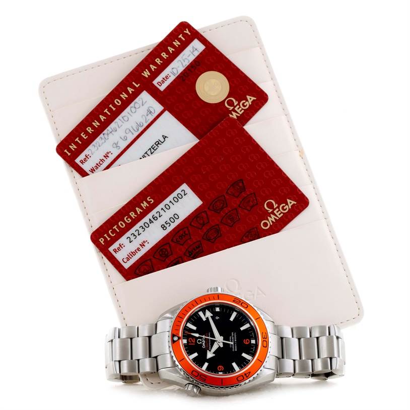 The image shows an Omega Planet Ocean 232.30.46.21.01.002 Men
s Stainless Steel Black Dial 232.30.46.21.01.002 Men
s Stainless Steel Black Dial watch with steel bracelet, laying beside its warranty and pictogram cards.