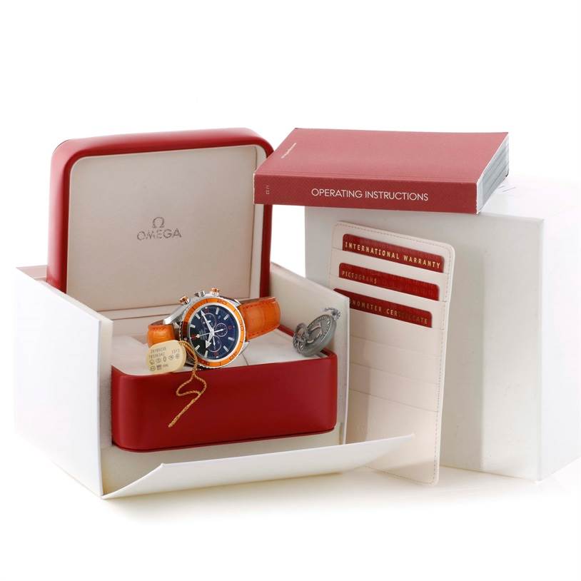 The image shows an Omega Planet Ocean 2918.50.38 Men
s Stainless Steel Black Dial 2918.50.38 Men
s Stainless Steel Black Dial watch at an angle inside its box, with operating instructions and warranty cards beside it.