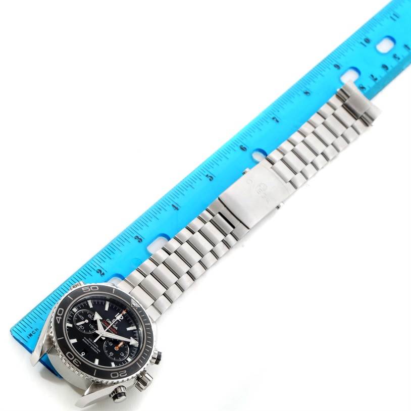 The Omega Planet Ocean 232.30.46.51.01.001 Men
s Stainless Steel Black Dial 232.30.46.51.01.001 Men
s Stainless Steel Black Dial watch is shown in a top-down angle with its face, bezel, and full metal bracelet visible next to a ruler.