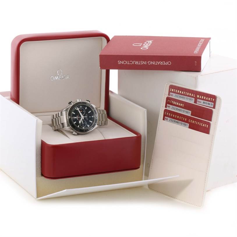 The image shows an Omega Planet Ocean 232.30.46.51.01.001 Men
s Stainless Steel Black Dial 232.30.46.51.01.001 Men
s Stainless Steel Black Dial watch in its box at a slight angle, with operating instructions and warranty cards.