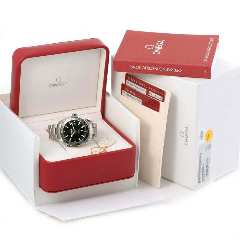 The image shows an Omega Planet Ocean 232.30.44.22.01.001 Men
s Stainless Steel Black Dial 232.30.44.22.01.001 Men
s Stainless Steel Black Dial watch in its open box, accompanied by an instruction manual, warranty cards, and outer box.