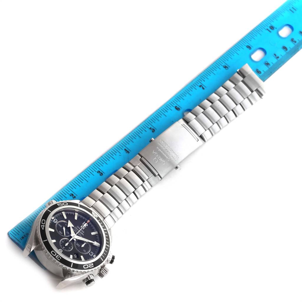 The image shows an Omega Planet Ocean 2210.50.00 Men
s Stainless Steel Black Dial 2210.50.00 Men
s Stainless Steel Black Dial watch laid flat with a blue ruler measuring its length.