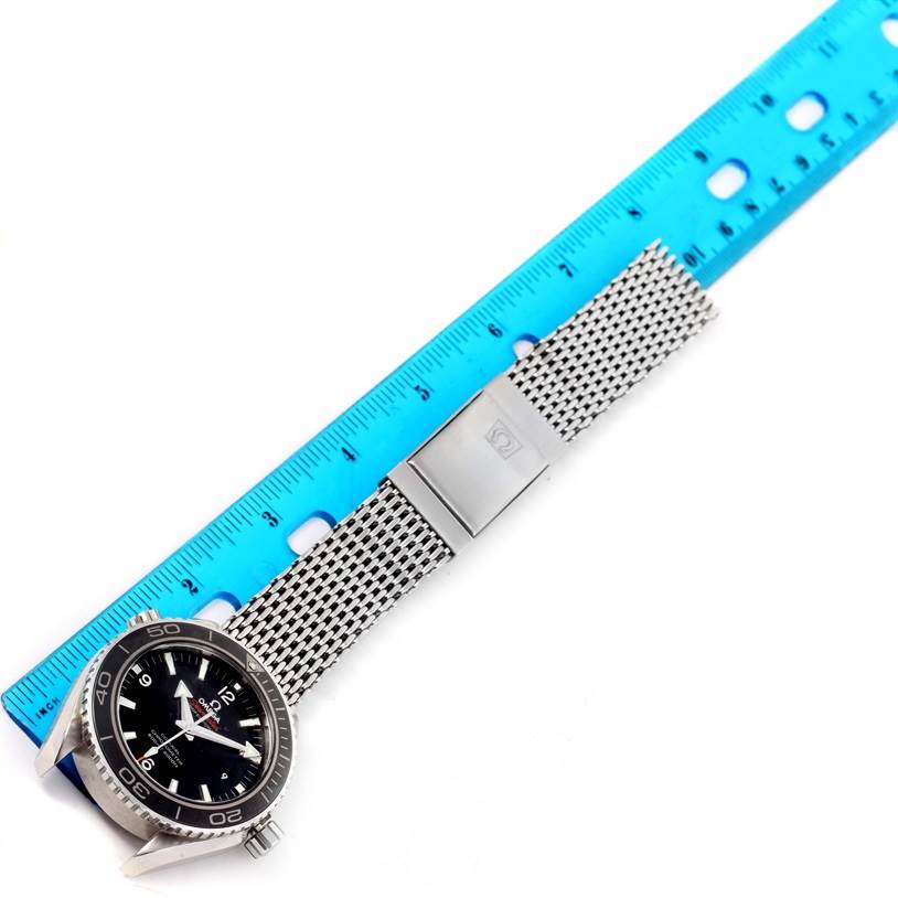 An Omega Planet Ocean 232.30.46.21.01.003 Men
s Stainless Steel Black Dial 232.30.46.21.01.003 Men
s Stainless Steel Black Dial watch is displayed flat with its silver mesh strap and clasp next to a blue measuring ruler.