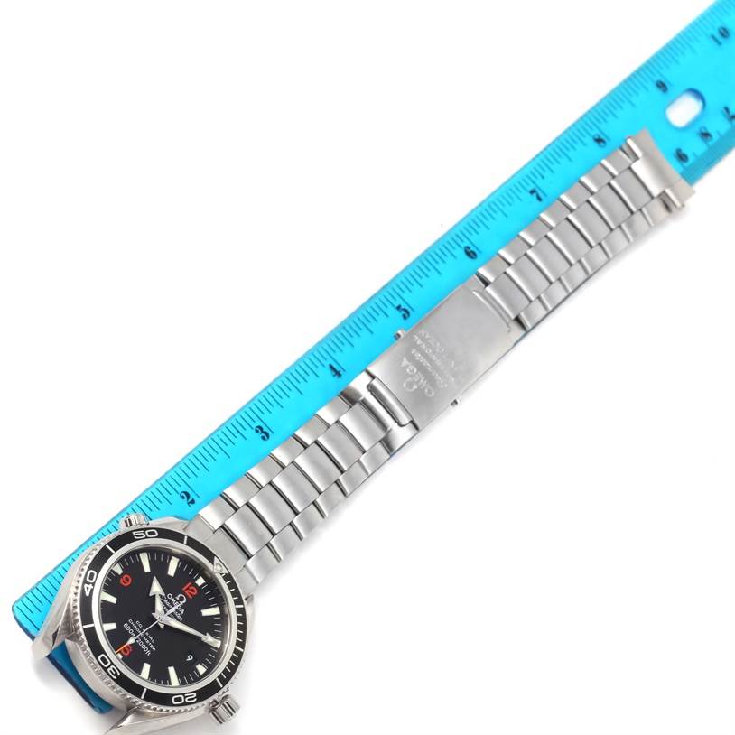 The image shows an Omega Planet Ocean 2201.50.00 Men
s Stainless Steel Black Dial 2201.50.00 Men
s Stainless Steel Black Dial watch laid flat alongside a ruler, displaying the dial, bezel, and bracelet with clasp.