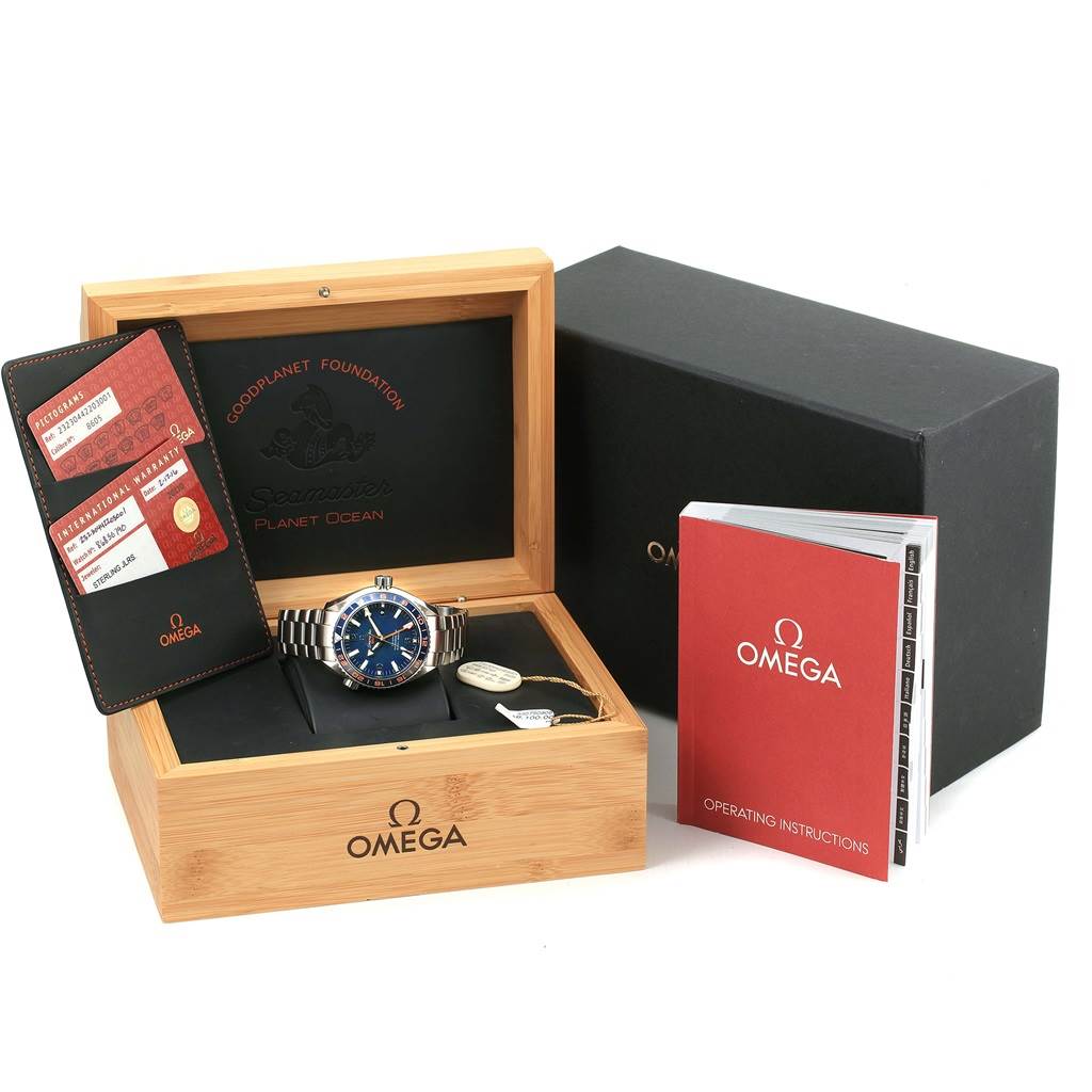 The image shows the Omega Seamaster Planet Ocean watch with its box, warranty card, and operating instructions.