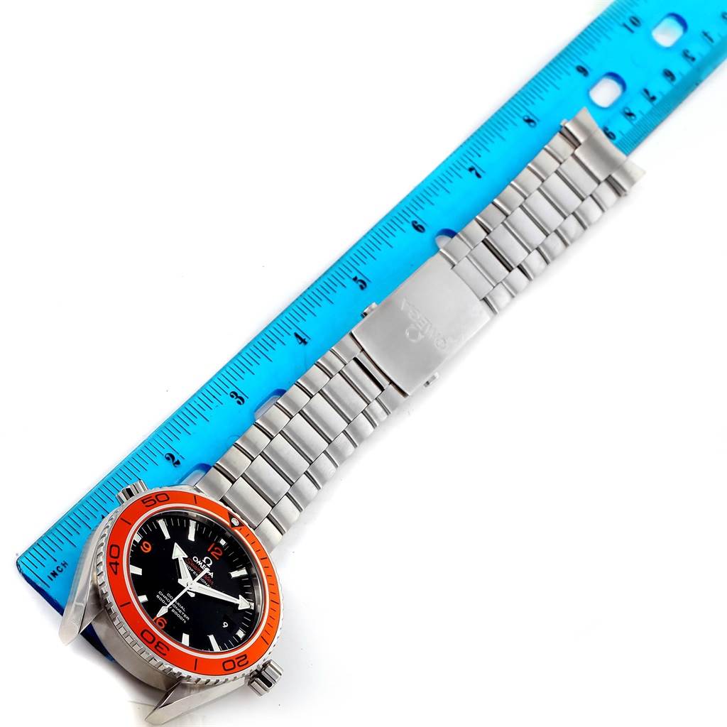 The image shows a top view of an Omega Planet Ocean 232.30.46.21.01.002 Men
s Stainless Steel Black Dial 232.30.46.21.01.002 Men
s Stainless Steel Black Dial watch, including the face, bezel, and metal bracelet, alongside a blue ruler.