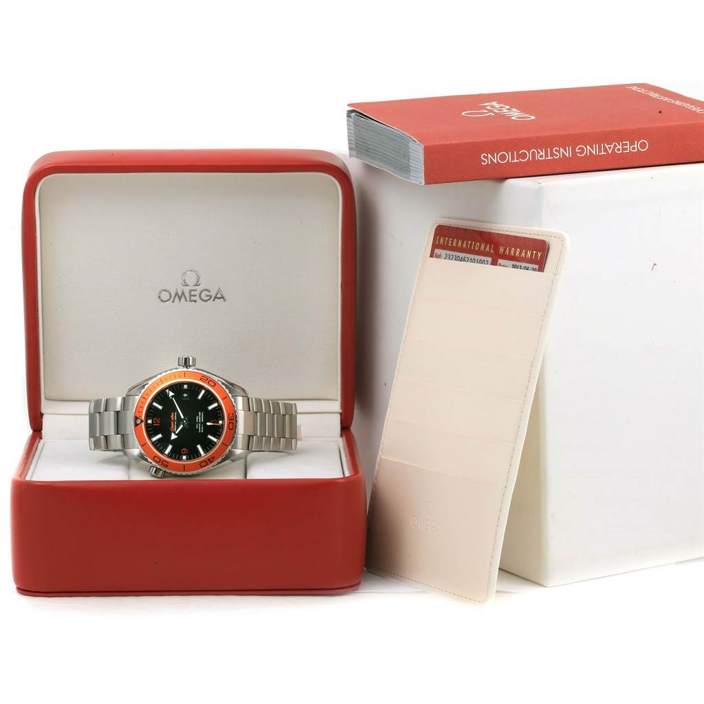 The image shows an Omega Planet Ocean 232.30.46.21.01.002 Men's Stainless Steel Black Dial 232.30.46.21.01.002 Men's Stainless Steel Black Dial watch in its open case, along with an instruction manual and a warranty card.