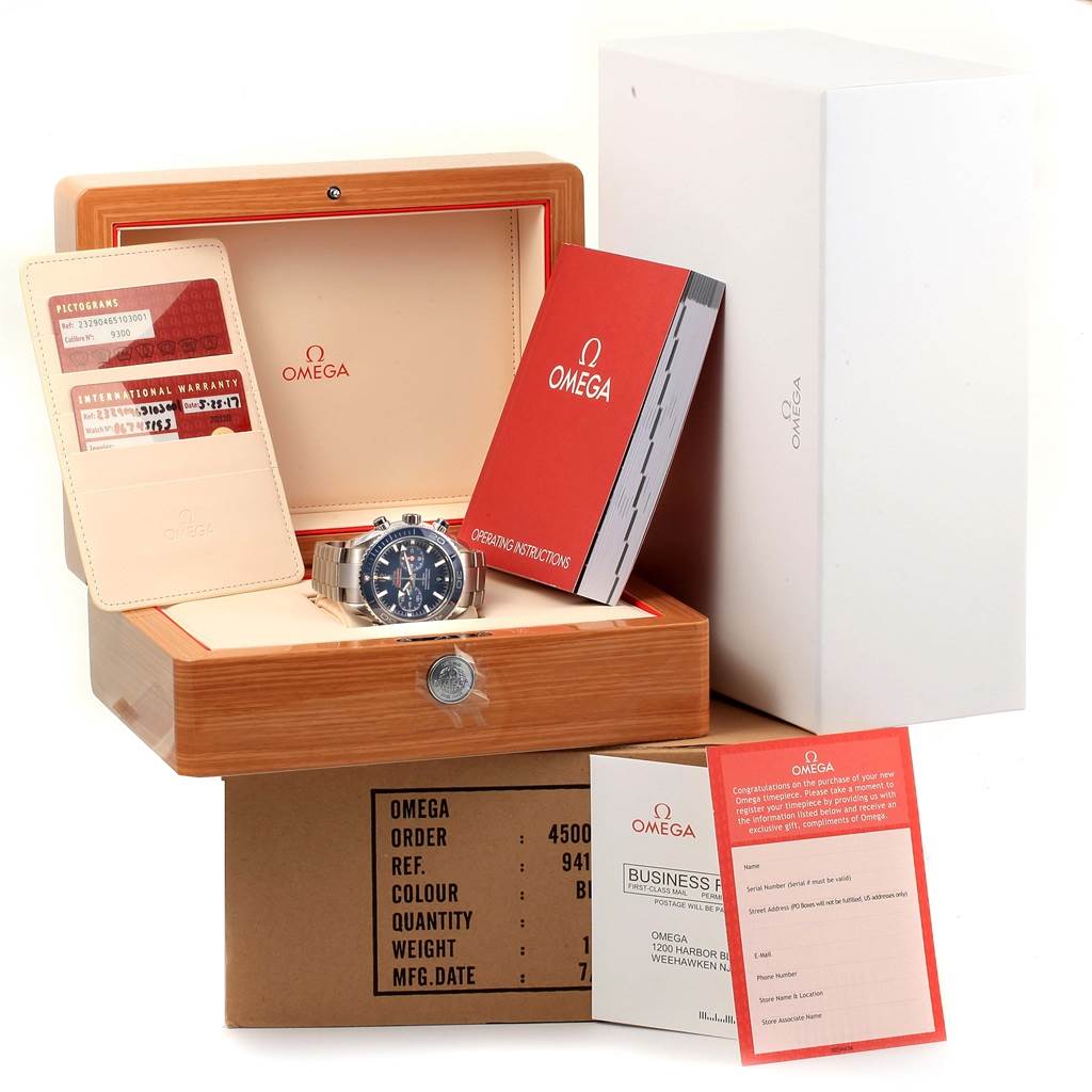 The image shows an Omega Planet Ocean 232.90.46.51.03.001 Men
s Titanium Blue Dial 232.90.46.51.03.001 Men
s Titanium Blue Dial watch with its accessories, including a warranty card, manuals, and both inner and outer boxes.