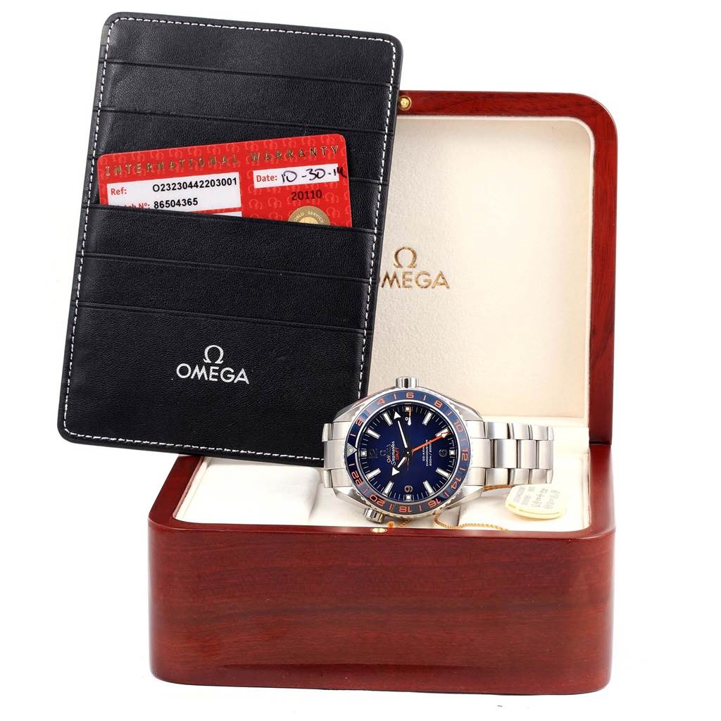 The Omega Planet Ocean 232.30.44.22.03.001 Men
s Stainless Steel Blue Dial 232.30.44.22.03.001 Men
s Stainless Steel Blue Dial watch is shown from a front angle, inside its box, accompanied by a warranty cardholder.