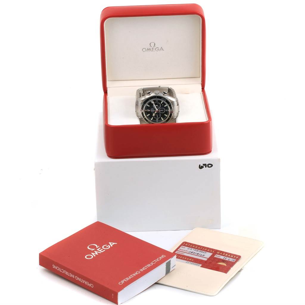 The image shows an Omega Planet Ocean 2210.50.00 Men's Stainless Steel Black Dial 2210.50.00 Men's Stainless Steel Black Dial watch front-facing in its box along with operating instructions and a warranty card.