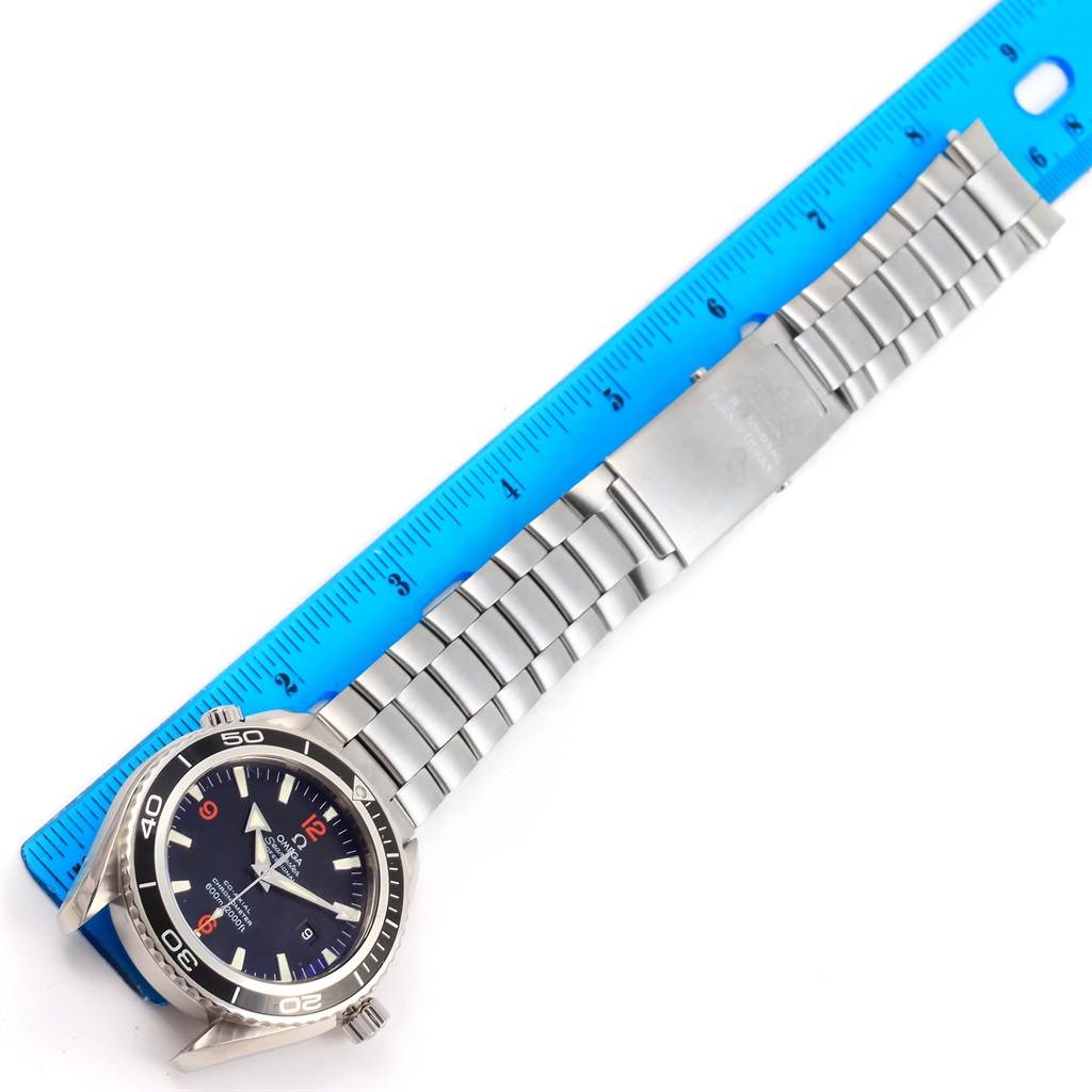 The image shows the Omega Planet Ocean 2200.51.00 Men
s Stainless Steel Black Dial 2200.51.00 Men
s Stainless Steel Black Dial model watch laid flat with its bracelet fully extended next to a blue ruler.