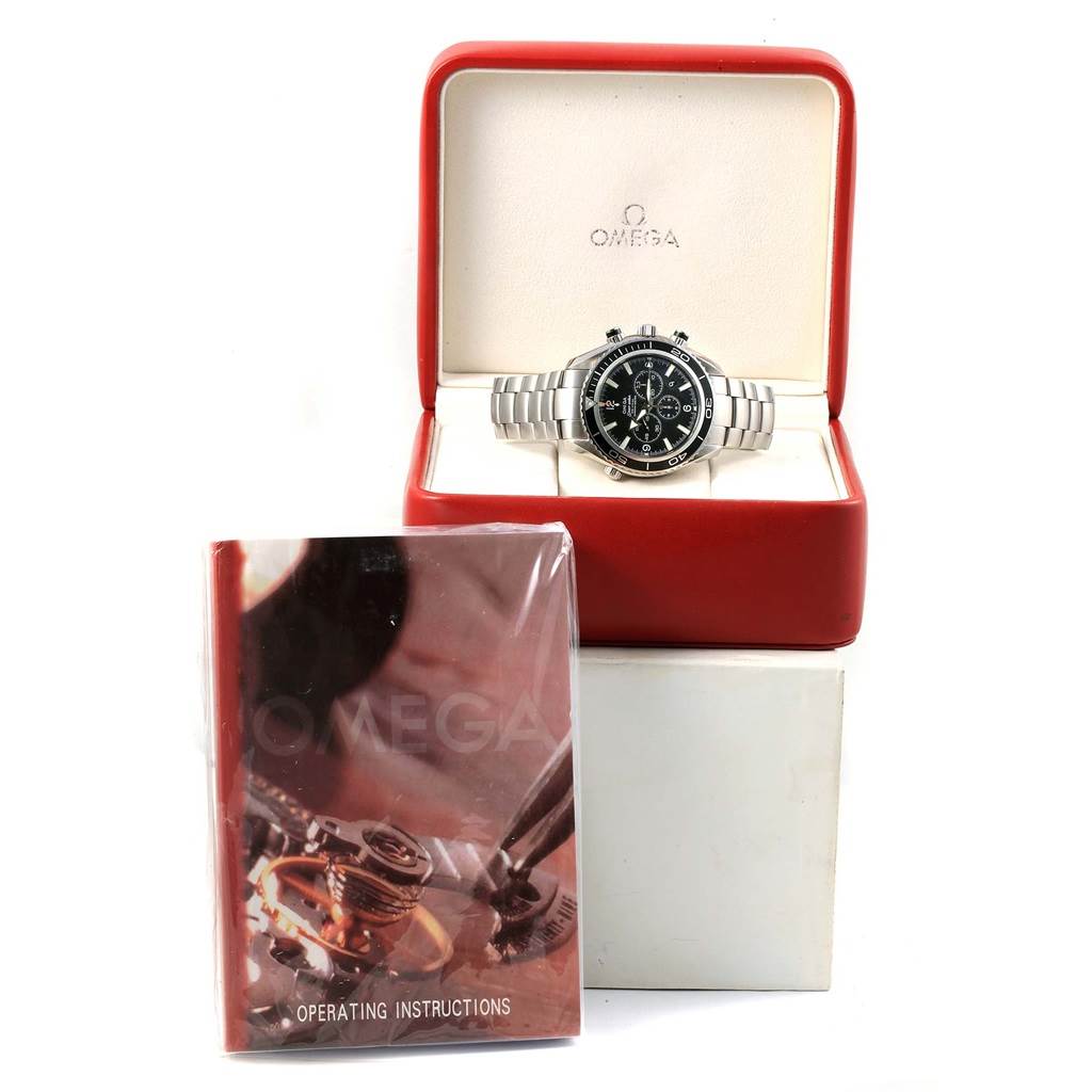 The Omega Planet Ocean 2210.50.00 Men
s Stainless Steel Black Dial 2210.50.00 Men
s Stainless Steel Black Dial watch is shown front-facing in its open case with an operating instructions booklet in front.