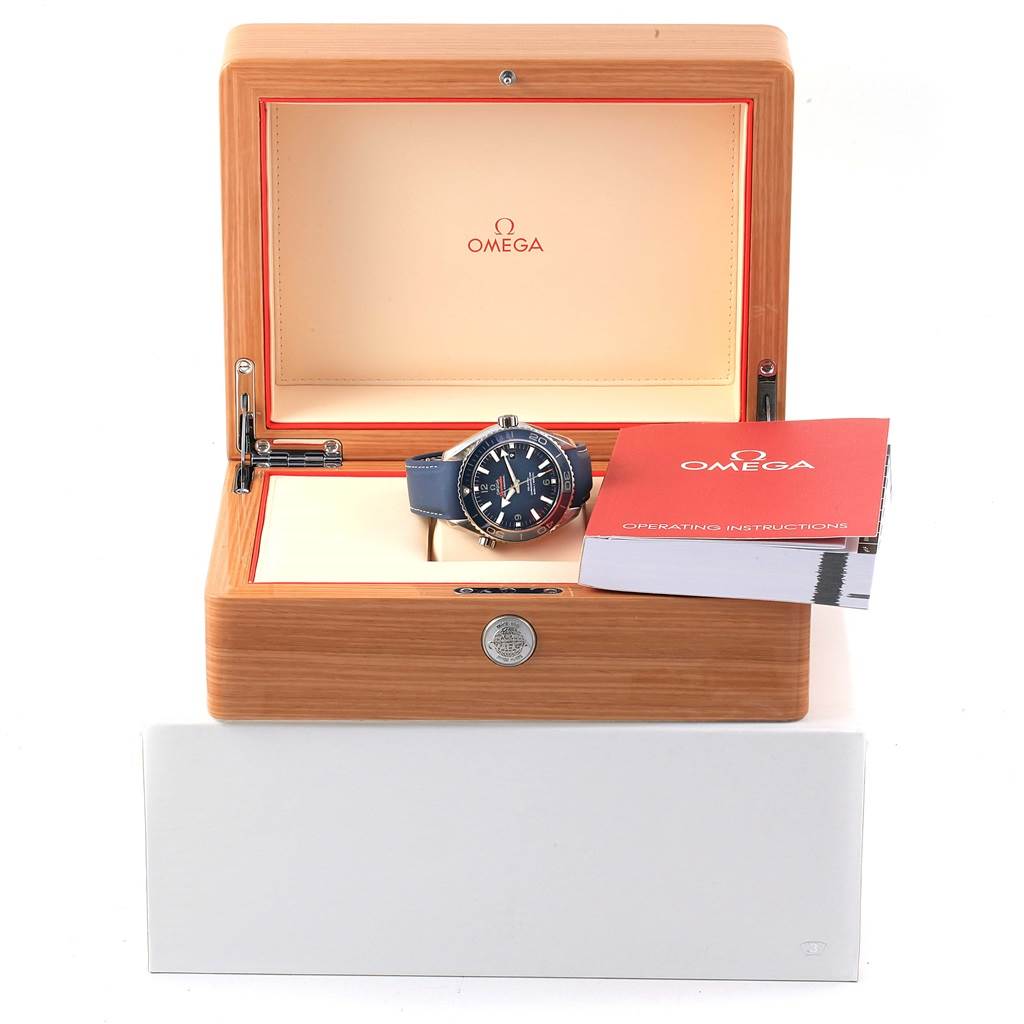 The image shows an Omega Planet Ocean 232.92.42.21.03.001 Men's Titanium Blue Dial 232.92.42.21.03.001 Men's Titanium Blue Dial model watch in an open wooden box with a manual beside it.