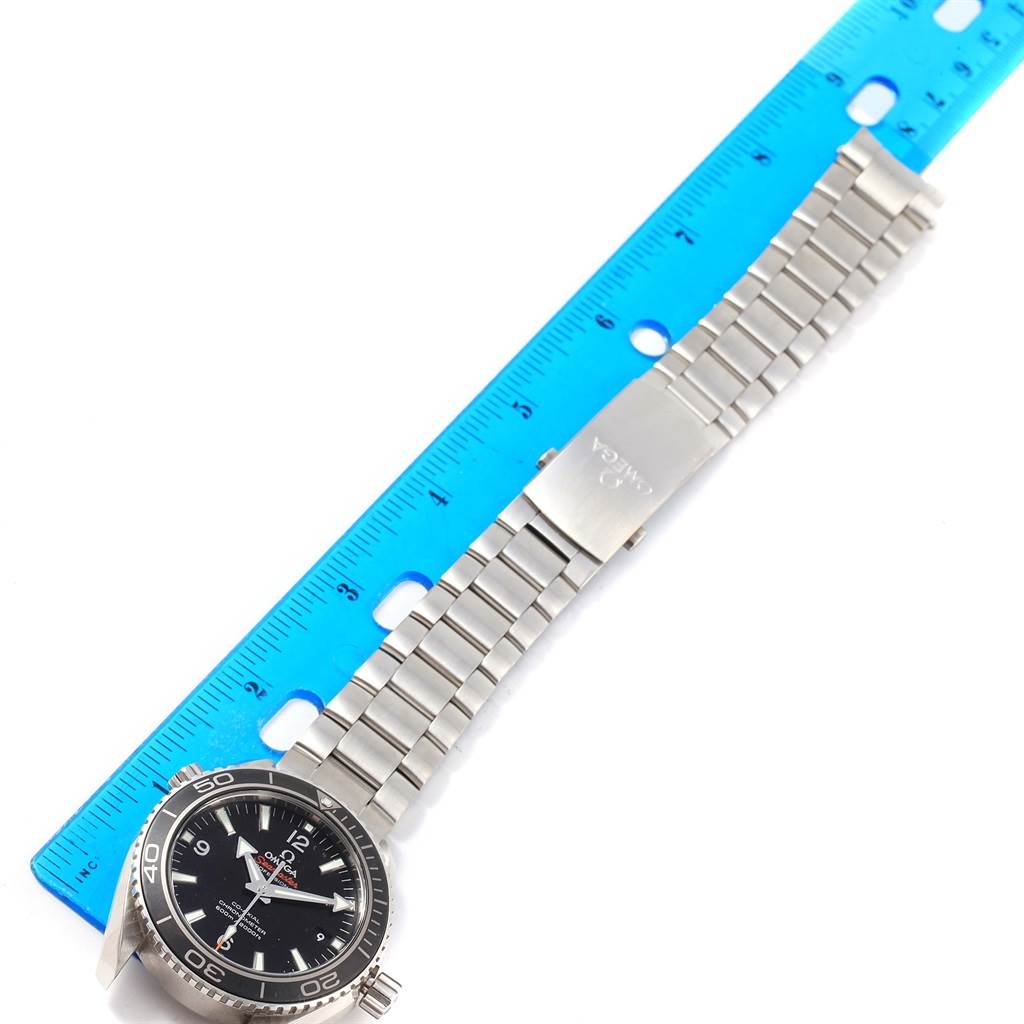 This image shows an Omega Planet Ocean 232.30.42.21.01.001 Men's Stainless Steel Black Dial 232.30.42.21.01.001 Men's Stainless Steel Black Dial watch, focusing on its face, bezel, and bracelet placed next to a blue ruler.