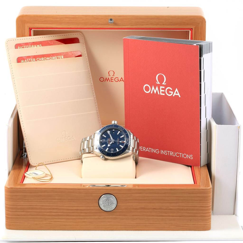The Omega Planet Ocean 215.30.40.20.03.001 Men's Stainless Steel Blue Dial 215.30.40.20.03.001 Men's Stainless Steel Blue Dial watch is displayed with its box, operating instructions, and certification cards in a frontal view.