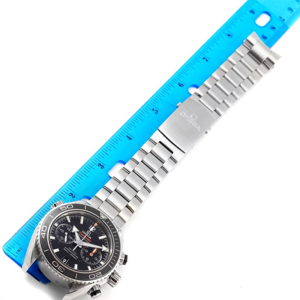 The Planet Ocean model by Omega is shown from an overhead angle, displaying the face, bezel, and bracelet alongside a blue ruler.